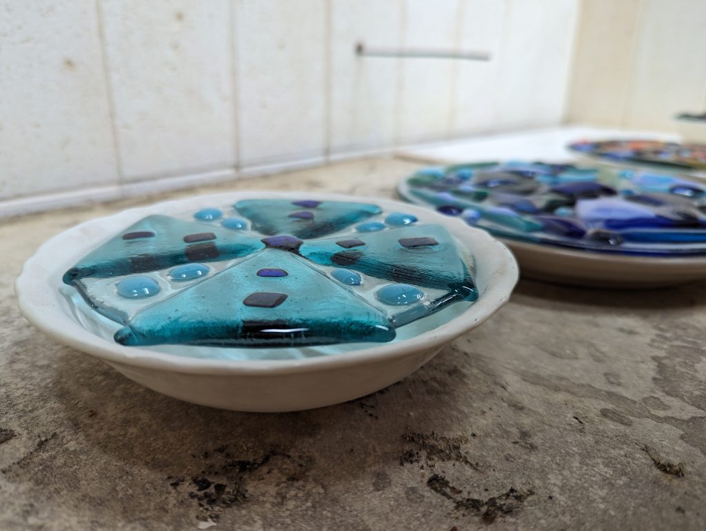 Fused glass sitting on ceramic bowl moulds before being slumped.